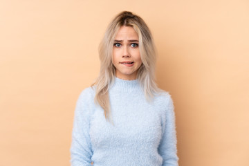 Teenager girl over isolated background having doubts and with confuse face expression
