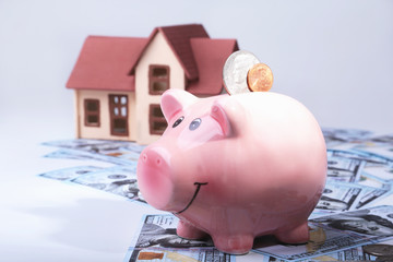 Real estate or home saving. piggy bank with coins on blur background money and house.