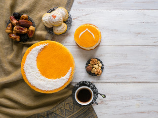 Festive food Ramadan background. Delicious homemade golden cake with a Crescent moon, served with black coffee and dates. Top view.