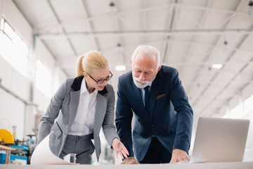 Colleagues working on project. Team of architects discussing business in factory.	