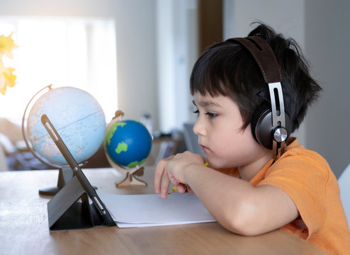 Kid Self Isolation Using Tablet For His Homework,Child Doing Using Digital Tablet Searching Information On Internet During Covid 19 Lock Down,Home Schooling,Social Distance,E-learning Online Education