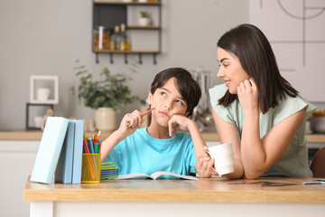 Obraz na płótnie Canvas Little boy with his mother doing homework in kitchen