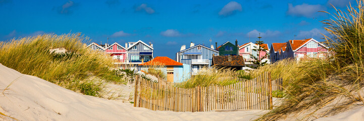 Idyllic and quaint beach houses seen from beach dunes. Beach houses with colorful stripes from...