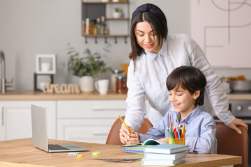 Little boy with his mother doing homework in kitchen