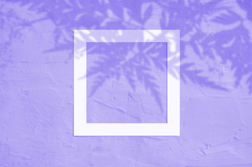Flat lay top view of creative copyspace with paper frame and tropical leaves palm shadow on violet color background.