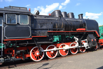 View of an old black locomotive with red wheels.