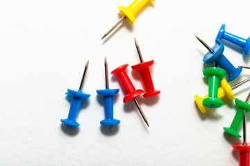 Sharp pin for attaching paper. Colored stationery buttons laid out on light background. Carnations for training. Attaching paper. Office stationery.