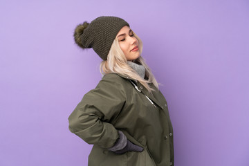 Teenager blonde girl with winter hat over isolated purple background suffering from backache for having made an effort