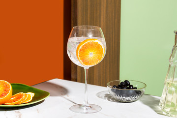 Gin tonic cocktail, garnished with orange slice, colorful background