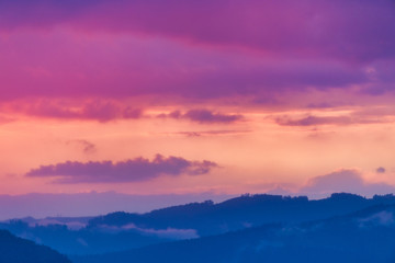 Sky above a mountain landscape at twilight, covered with colorful clouds.