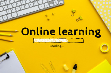 Flat lay work desk with keyboard, stationery and phrase ONLINE LEARNING on a yellow background