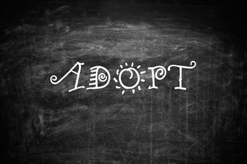Obraz premium Word ADOPT written with chalk on blackboard, top view. Family concept