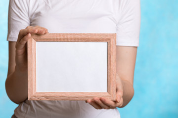 a young woman holds a wooden frame with an empty text field