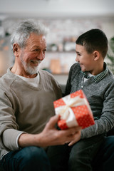 Grandfather giving gift to grandson.	