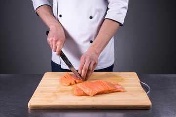 Obraz na płótnie Canvas chef cuts salmon for fresh sushi in a restaurant kitchen6
