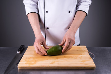 chef cuts and cleans a ripe avocado in the restaurant kitchen