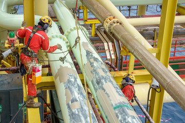 Working at height. A group of abseilers wearing Personal Protective Equipment (PPE) standing on the structure for pipeline touch up painting activities.