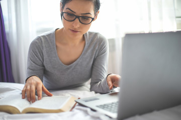 Woman with bible and laptop in front of her connected to online church services durring the covid 19 outbreak