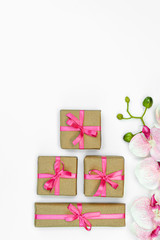 Obraz na płótnie Canvas flatlay Gift present boxes pink ribbon, orchid flowers on white backgroun. spring concept. Copy space