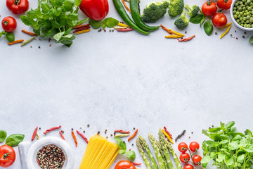 Frame for Italian food. Ingredients for pasta. Cherry tomatoes, meat, spaghetti pasta, garlic, Basil, asparagus, broccoli and spices on a grey grunge background, copy space, top view
