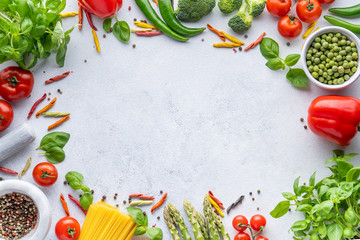 Frame for Italian food. Ingredients for pasta. Cherry tomatoes, meat, spaghetti pasta, garlic, Basil, asparagus, broccoli and spices on a grey grunge background, copy space, top view
