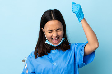 Young brunette mixed race dentist woman holding tools over isolated background celebrating a victory