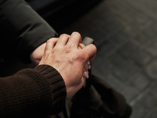 Two hands of people in love on the handle of a suitcase, traveling together
