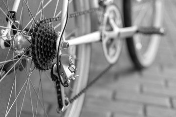 Old mountain bike against the wall. Repair of retro bicycles. Bicycle as a means of preserving health. Fashionable bicycle for teenagers. Rear derailleur of the close-up. Black and white image