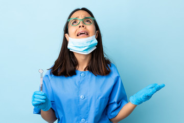 Young brunette mixed race dentist woman holding tools over isolated background stressed overwhelmed