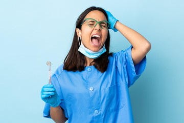 Young brunette mixed race dentist woman holding tools over isolated background stressed overwhelmed