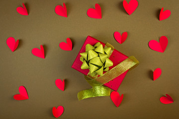 Holiday gift in a red box and with a gold ribbon many hearts, the concept of the holiday, love and Valentine's Day,place for text