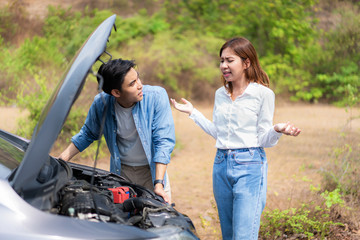 Asian young couple with man and woman on the road having problem breakdown down car engine on the road and woman looking stress when a man can not repair car..