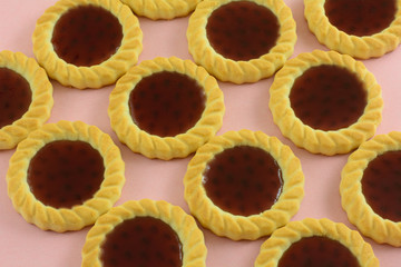 Close up of red raspberry fruit tartlette cookies on pink background