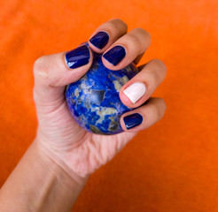 Hand with nail polish, blue and white, grabbing a sodalite rock.