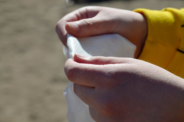 The girl is holding a wet cloth to wipe her hands. A young girl wipes her hands with a disinfectant napkin. Close up. Hand hygiene in a pandemic.