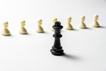 chess king is standing against white pawns. Symbol of leadership and confrontation. Horizontal frame