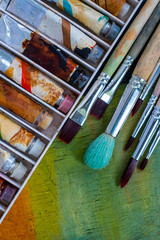 paints and brushes are on canvas