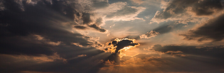 panorama of sun breaking through clouds at sunset amazing sky background