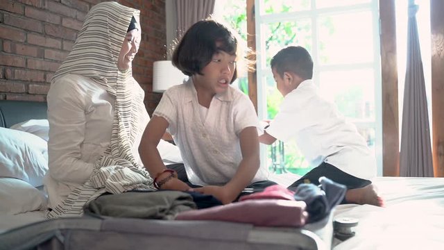 Mother and her child prepare clothes and suitcase for carried when mudik go to the village
