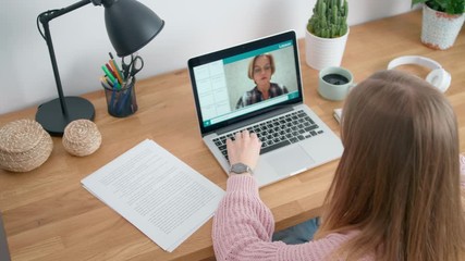 Female Student Study Online and Learns Video Lesson with Teacher using Laptop at Home. E-learning Classe, Webinar, Distance course or Workshop concept at COVID-19 Pandemic. 4K Top View Orbit Shot