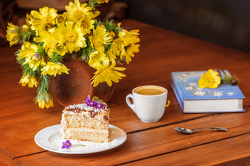 A moment of relaxation, morning coffee with a delicious cake. Yellow adonis flowers on a wooden table