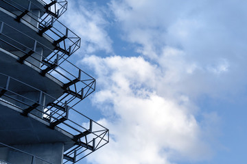 Part of a building under construction. Fragment of concrete metal structures on a background of blue sky with clouds. Construction of a multi-level parking, residential building, commercial property.