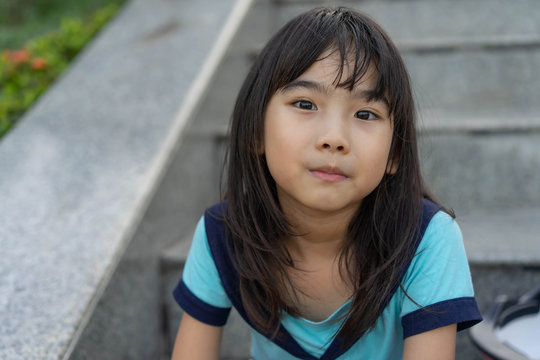 Portrait Asian cute child girl 7 years old smiling happy sit relax After exercising in the park