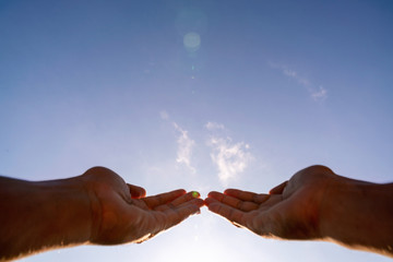 Blurred Hands praying for blessing from god on sun and clouds background with lens flare,Christian Religion concept.