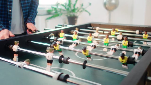 Friends playing table soccer game miniatur football brasil vs germany white versus yellow shot in 4k