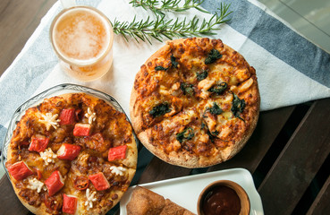 Fresh beer in the glass with Homemade pizza on the background closeup. Selective focus with light from the window
