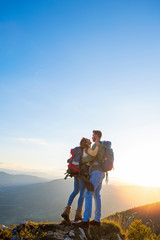 Hikers with backpacks relaxing on top of a mountain and enjoying the view of valley