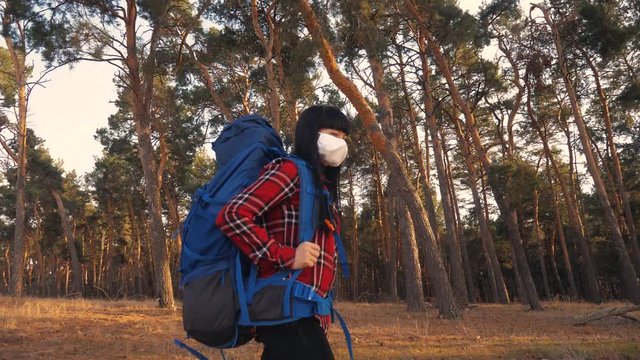 tourist hiker girl goes for a walk near a hiking backpack lifestyle forest park. concept pandemic virus epidemic world catastrophe infection covid