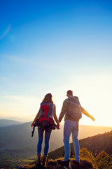 Fototapeta premium Hikers with backpacks relaxing on top of a mountain and enjoying the view of valley