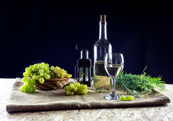 Bottles of wine, glassful and grapes on a black background close-up
